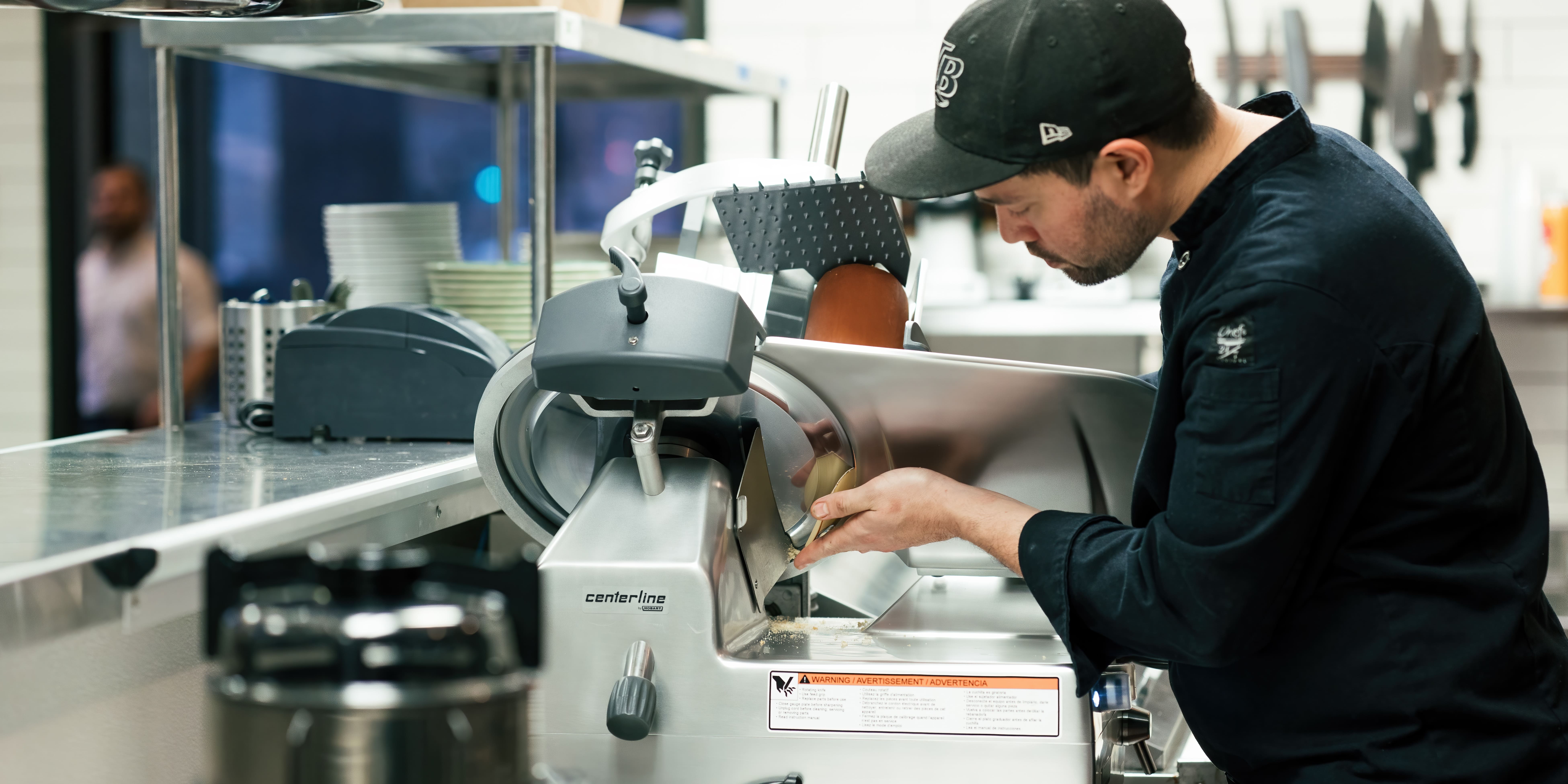 A man uses a Centerline slicer in a kitchen