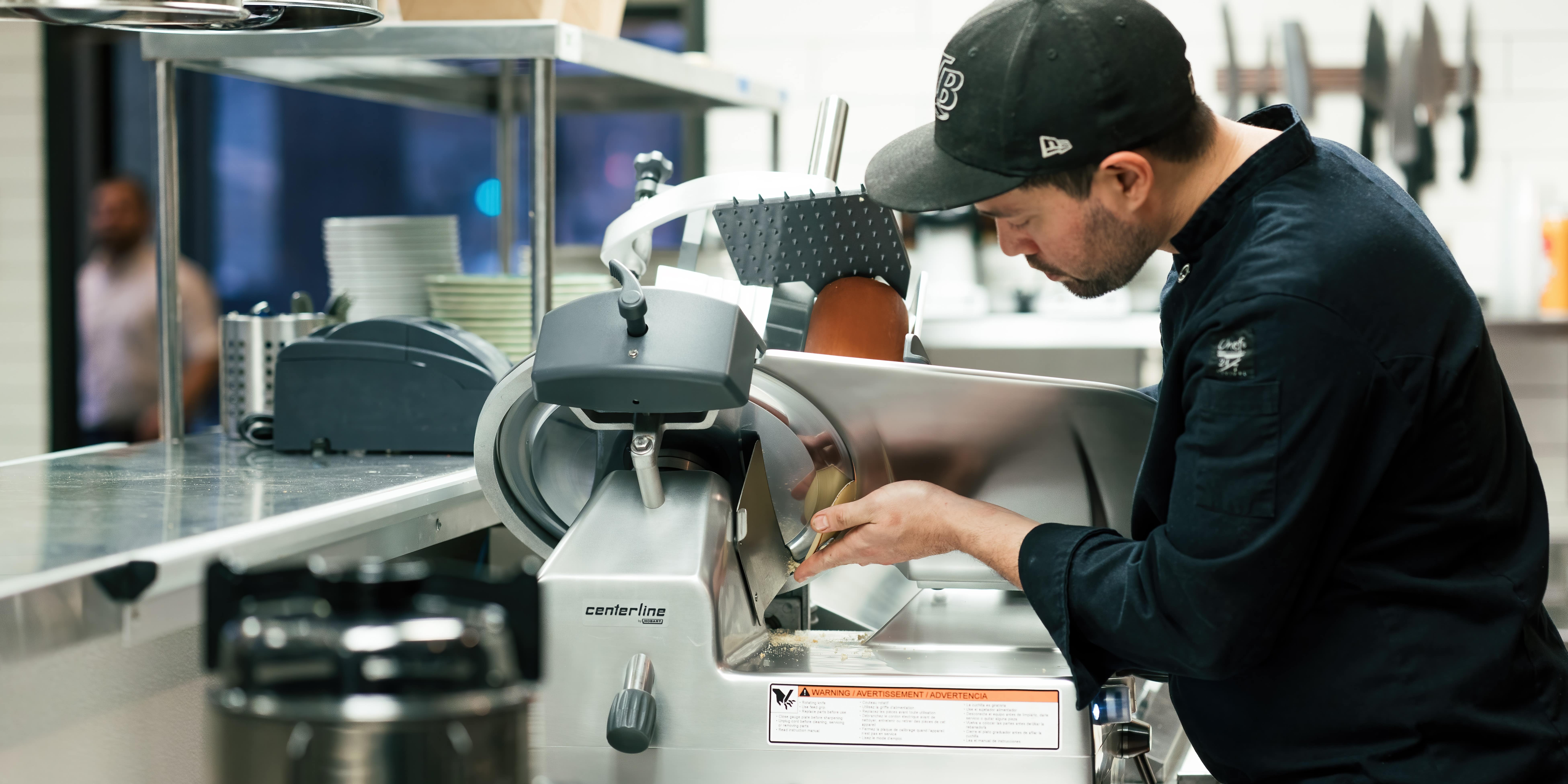 A chef uses a Centerline by Hobart commercial slicer