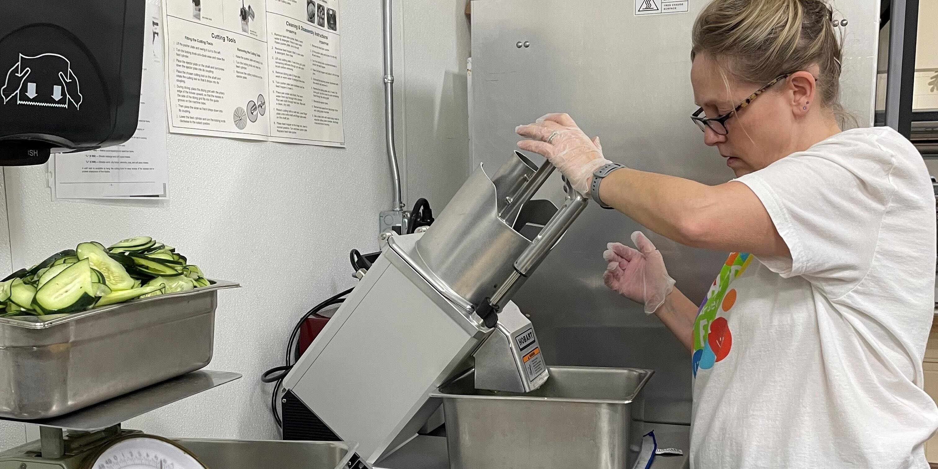 A food service worker uses the Hobart FP150 food processor at Greendale High School