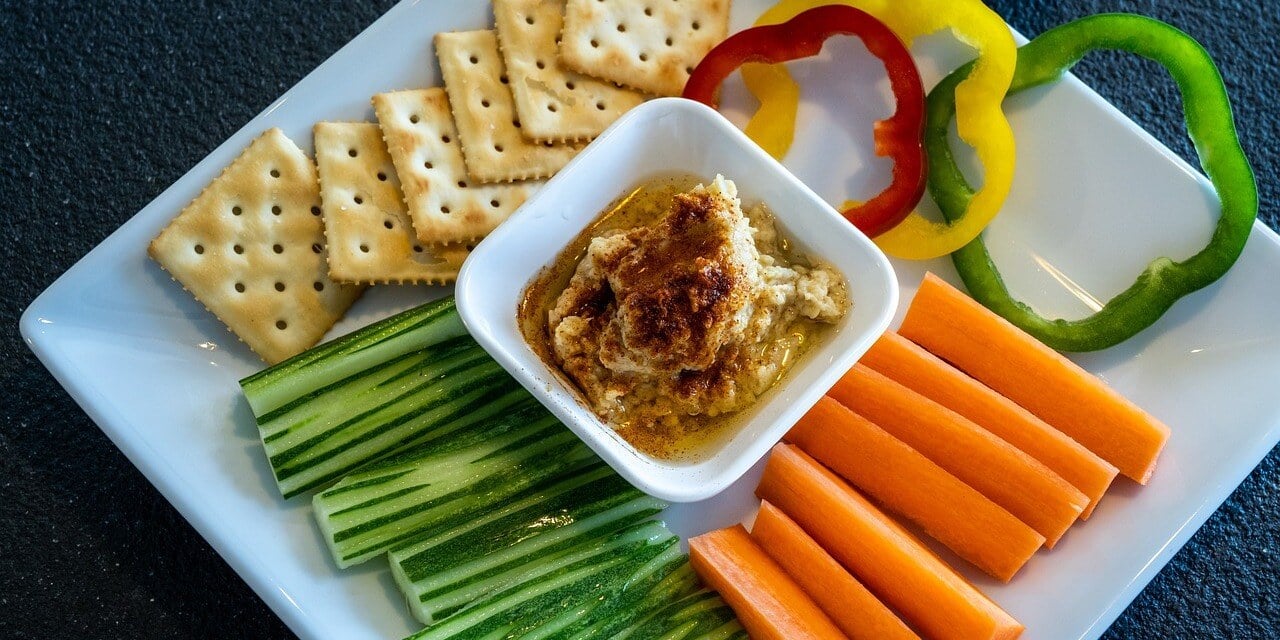Hummus on a plate with crackers and vegetables